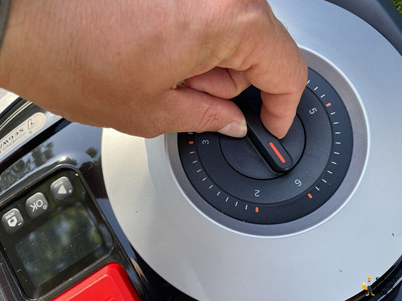 Ein kleines Ziffernblatt ist oben auf dem Segway Navimow i108E Mähroboter, um die Schnitthöhe zwischen 2 und 6 cm zu verstellen.